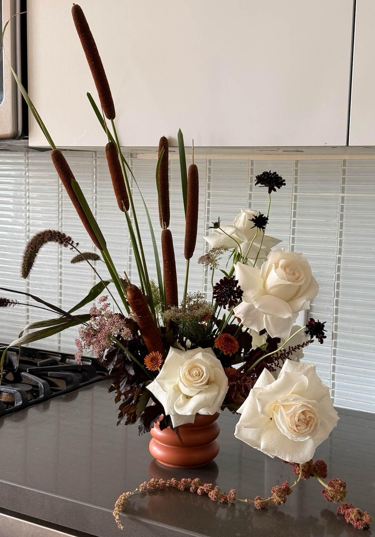 Terracotta Dusk adds autumn warmth to a kitchen, with white roses and seasonal flowers in a terracotta pot